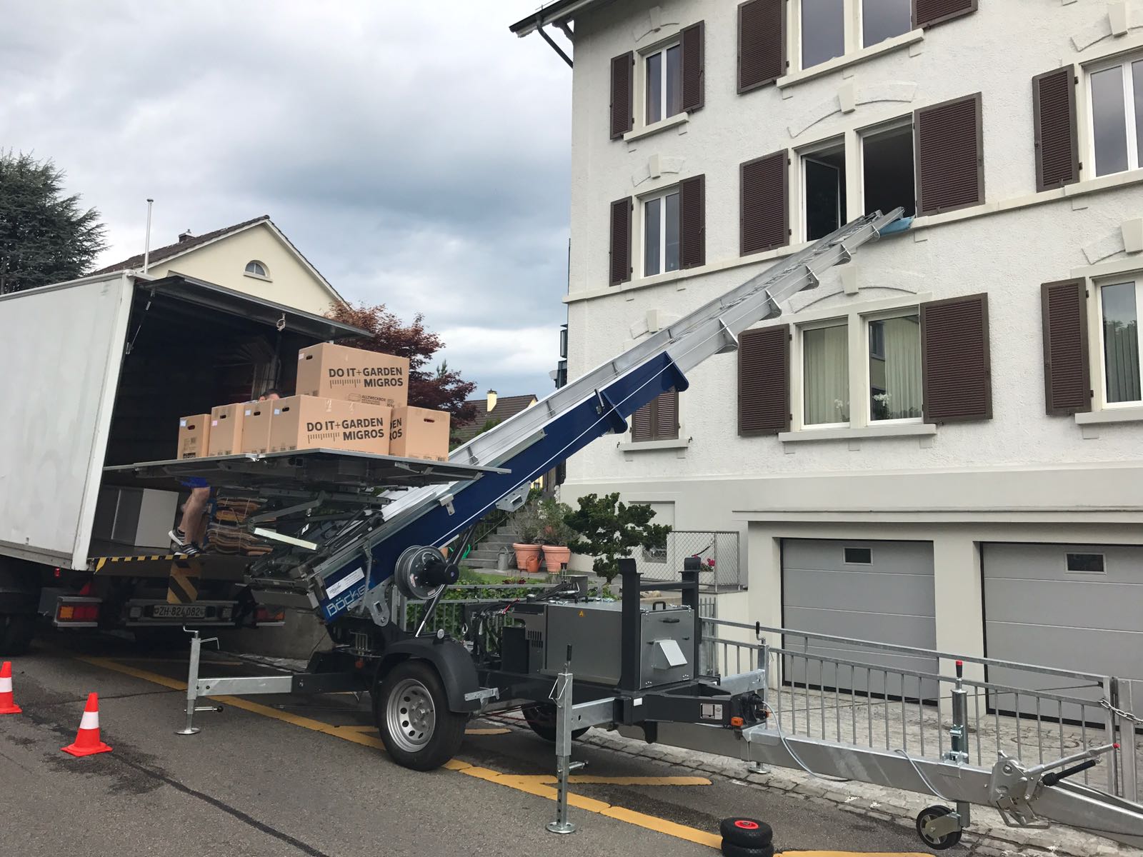 Umzugsdienst mit Möbelaufzug, Kartons im Umzugswagen, Wohnhaus mit Fenster, stressfreier Umzug in Zürich.