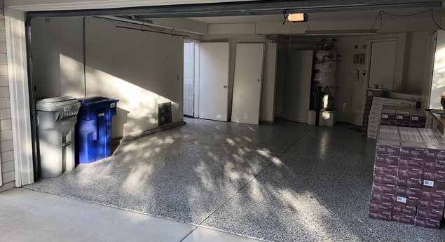 Leerer Garagenraum mit Mülltonnen, sauberem Boden und gestapelten Materialien, ideal für Entrümpelung und besenreine Übergabe nach Haushalts- oder Büroauflösungen.